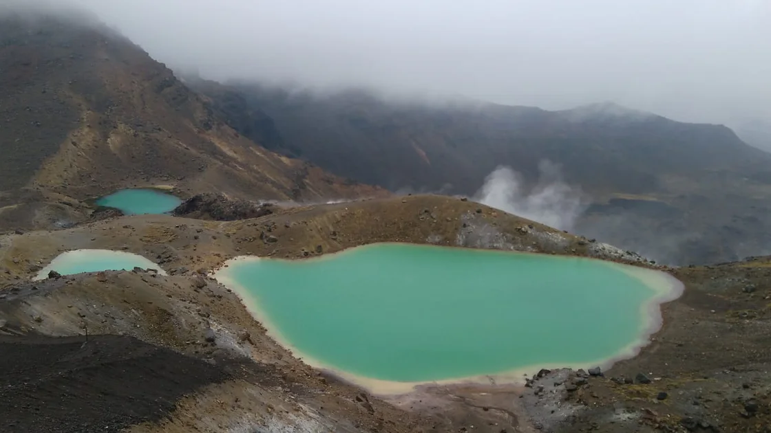 Turquoise crater lakes with rising steam in a geothermal volcanic landscape