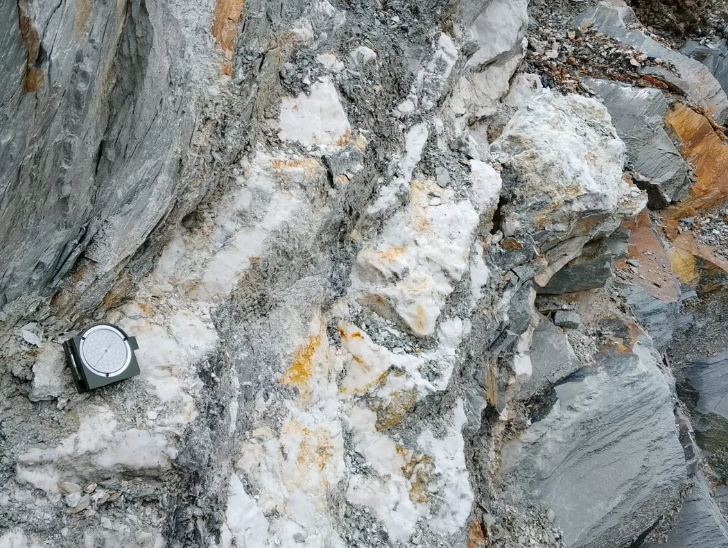 A geological compass resting on a pale vein surface for orientation measurement