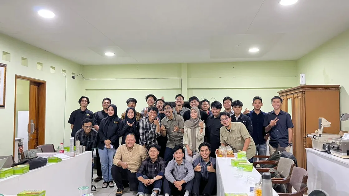 A group posing together in a technical meeting room